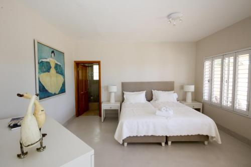 a white bedroom with two beds and a window at Stella Maris Luxury Apartment in Plettenberg Bay