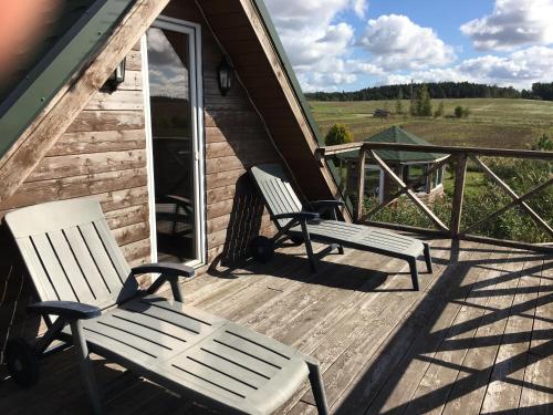 two chairs sitting on a porch of a cabin at Svečių namelis - Pirtis in Vydmantai