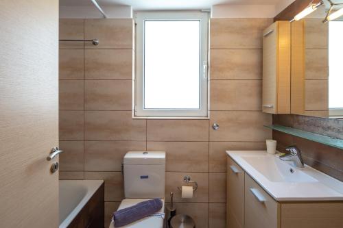 a bathroom with a toilet and a sink and a window at Solon - Deluxe City Center Apartment in Athens