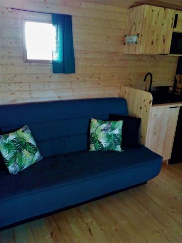 - un canapé bleu avec deux oreillers dans l'établissement Les Cabanes de Gros Bois, à Prailles