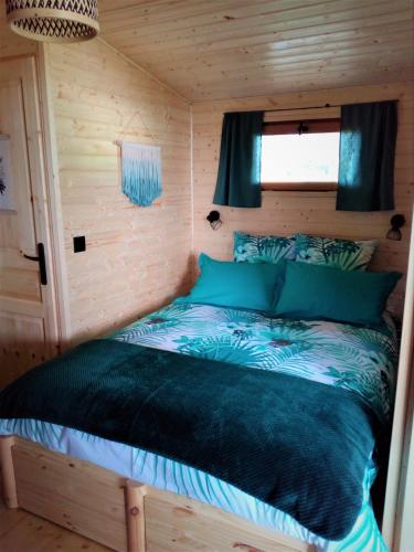 Ce lit se trouve dans une cabane en rondins dotée d'une fenêtre. dans l'établissement Les Cabanes de Gros Bois, à Prailles