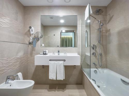 a bathroom with a sink and a mirror and a tub at Hotel Maestranza in Ronda