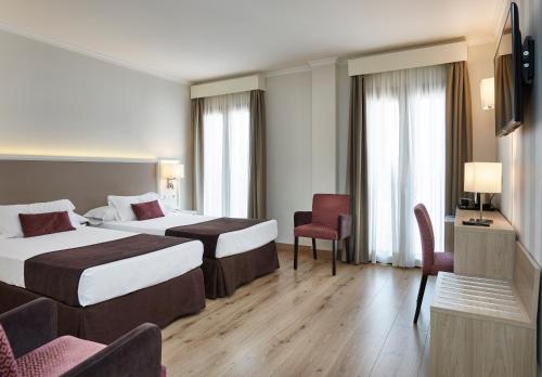 a hotel room with two beds and a television at Hotel Maestranza in Ronda