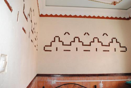 a wall with a castle stencil on it at Auberge Restaurant Rooftop Tamazirt in Boumalne