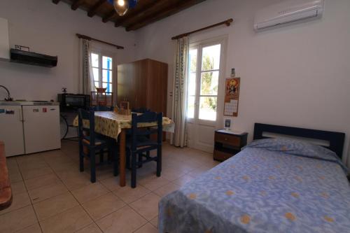 a bedroom with a bed and a table and a kitchen at Smaragda Rooms & Studios in Platis Gialos