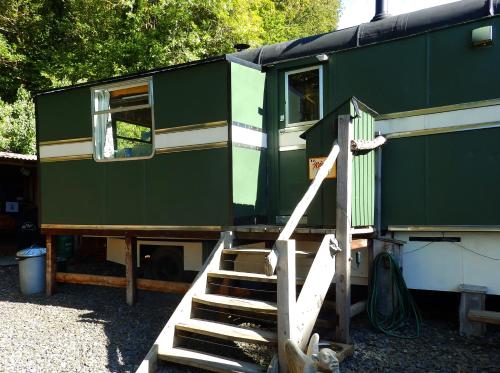 a green train car with a staircase leading to it at Showman's Wagon at Coed Cae in Dolgellau
