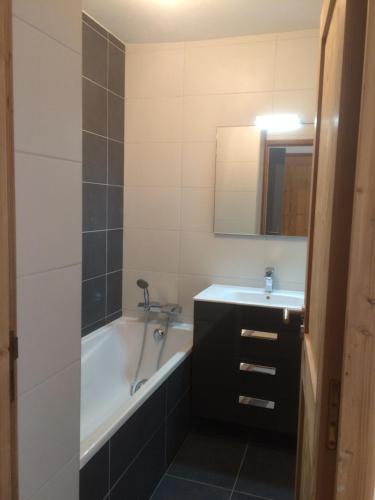 ein Badezimmer mit einer Badewanne, einem Waschbecken und einem Spiegel in der Unterkunft 63 Route du Rochas in Vaujany