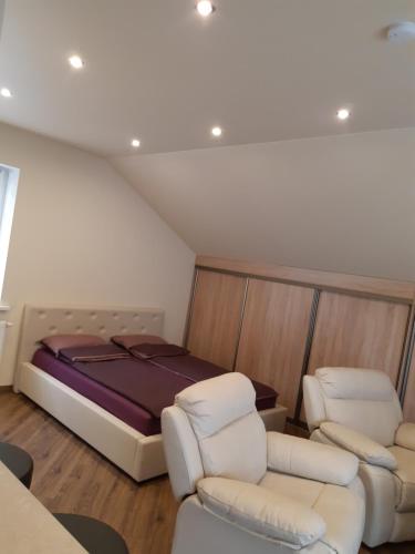 ein Schlafzimmer mit einem Bett und zwei weißen Stühlen in der Unterkunft Zveryno guest house in Vilnius