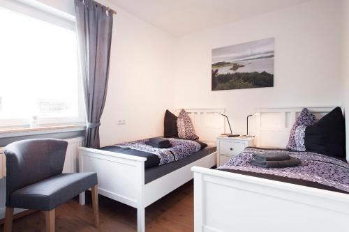 Duas camas num quarto com uma cadeira e uma janela em Gästehaus „bei Pohls“ em Bruchhausen-Vilsen