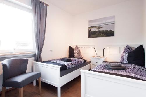 two beds in a room with a chair and a window at Gästehaus „bei Pohls“ in Bruchhausen-Vilsen