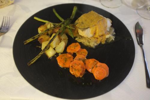 a black plate of food with carrots and potatoes at Hotel Rural La Paloma in Villanueva de Tapia