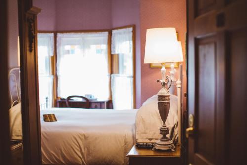 a bedroom with a bed and a lamp on a table at Albergo Allegria Hotel & Breakfast Restaurant in Windham