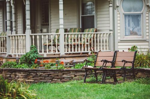 a bench sitting in the grass in front of a house at Albergo Allegria Hotel & Breakfast Restaurant in Windham