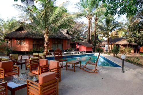 a resort with a pool with chairs and a house at Fromager in Cap Skirring