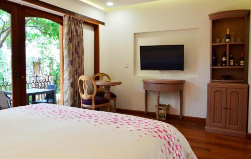 a bedroom with a bed and a flat screen tv at La Casa Del Arbol Hotel Boutique Villa de Leyva in Villa de Leyva