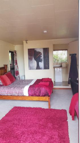 a bedroom with two beds and a pink rug at Pohutukawa Coast BnB in Te Puru