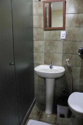 a bathroom with a sink and a mirror and a toilet at Hotel Galícia in Rio de Janeiro