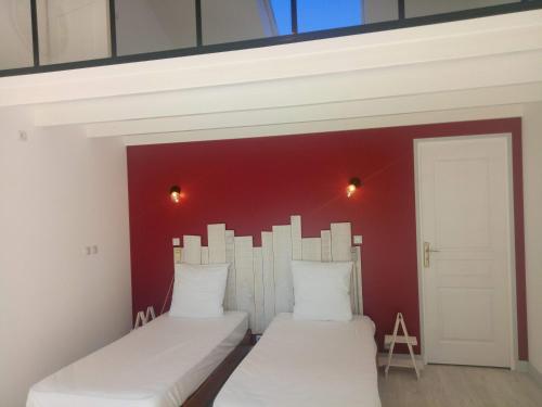 Dos camas en una habitación con una pared roja. en B&B le 3 étoiles, en Mayet