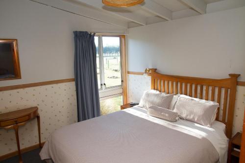 a bedroom with a white bed and a window at Stronechrubie Accommodation and Restaurant in Mount Somers