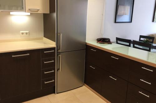 a kitchen with black cabinets and a stainless steel refrigerator at Apartamento Calafell playa in Calafell