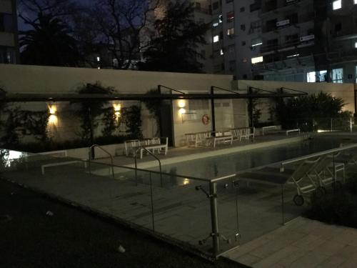 a swimming pool with chairs and lights at night at 629 Serrano in Buenos Aires