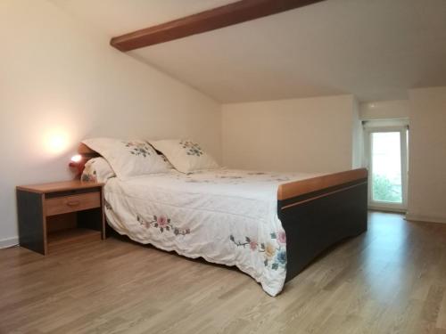 Schlafzimmer mit einem Bett und Holzboden in der Unterkunft Studio mansardé à Oyonnax in Oyonnax