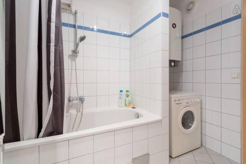 a bathroom with a tub and a washing machine at Relaxing Terrace Apartment in Lively Area in Vienna