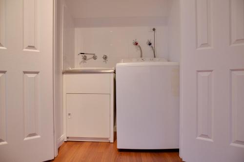 a white bathroom with a sink and a refrigerator at Sapphire Cottage in Glen Innes