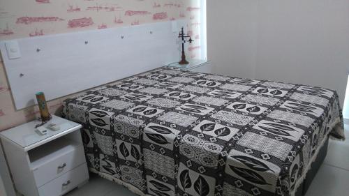 Schlafzimmer mit einem Bett mit einer schwarzen und weißen Tagesdecke in der Unterkunft Le Bon Vivant in Arraial do Cabo