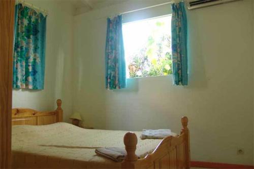 1 dormitorio con 1 cama y una ventana con cortinas azules en La Kallina, en Grand-Bourg