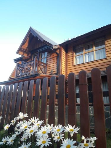 a wooden fence in front of a house with flowers at Ushuaia Lodge in Ushuaia