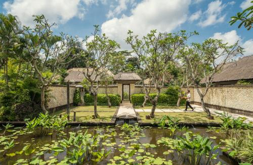 a person walking through a garden with a pond at Four Seasons Resort Bali at Jimbaran Bay in Jimbaran