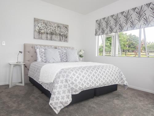 a white bedroom with a large bed with a window at The Rise in Waimate North