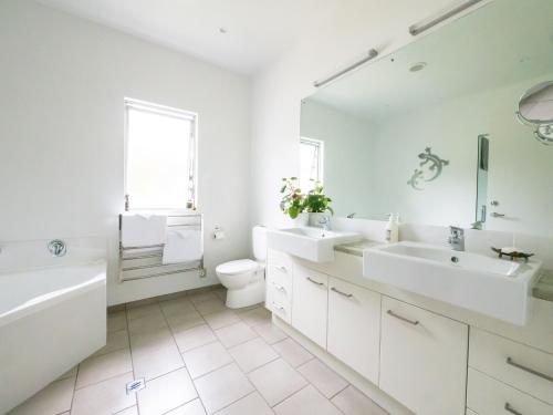 a white bathroom with two sinks and a toilet at The Rise in Waimate North