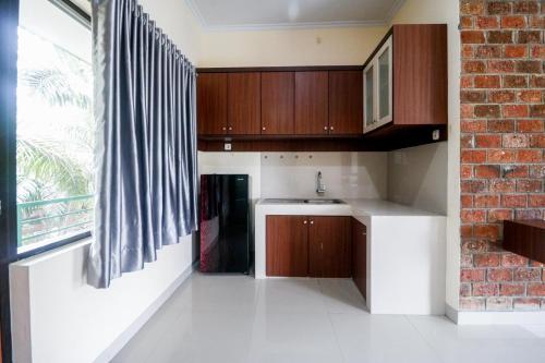 a kitchen with wooden cabinets and a brick wall at RedDoorz Plus near Kualanamu Airport Medan in Medan