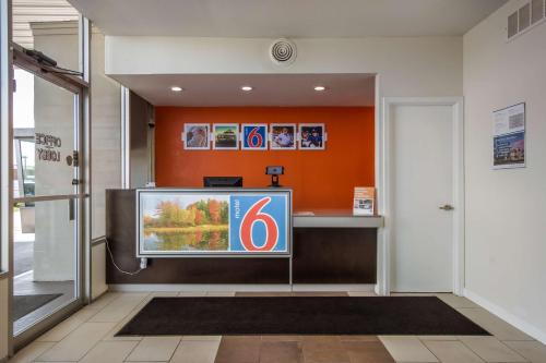 a television in a lobby with an orange wall at Motel 6-Van Buren, AR I- 40 in Van Buren