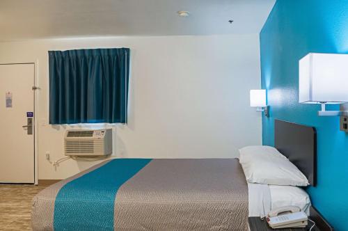 a small room with a bed and a blue wall at Motel 6-Bay Saint Louis, MS in Bay Saint Louis