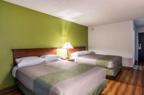 two beds in a hotel room with green walls at Motel 6-Petersburg, VA - Fort Lee in Petersburg