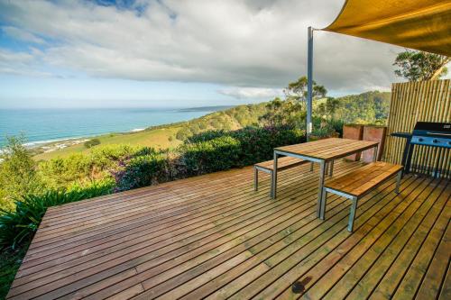 a wooden bench sitting on top of a sandy beach at Beacon Point Ocean View Villas in Apollo Bay