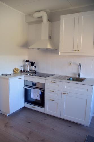 a white kitchen with white cabinets and a sink at Putiikkihotelli Kemi 1932 in Kemi