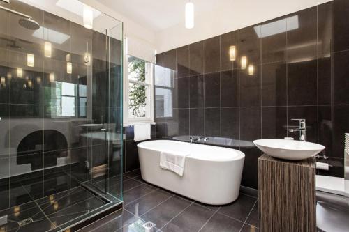 La salle de bains est pourvue d'une baignoire, d'un lavabo et d'une douche. dans l'établissement The Crofts, à Melbourne