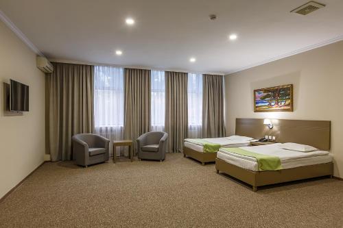 a hotel room with two beds and two chairs at Renion Hotel in Almaty