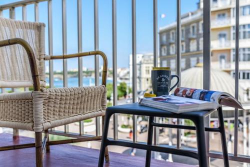 a table and a chair on a balcony with a drink at Hotel De L'Océan in Biarritz