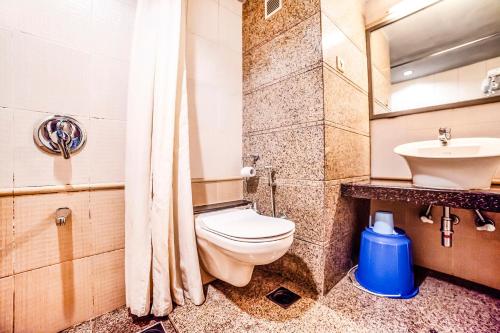 a bathroom with a toilet and a sink at Hotel Gandharva Shivajinagar in Pune
