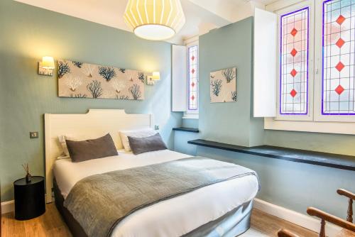 a bedroom with a bed and two windows at Hotel De L'Océan in Biarritz