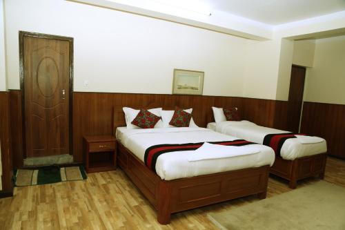 two beds in a room with wood paneling at Green Eco Resort in Kirtipur