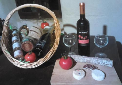 a basket of wine and a bottle and glasses on a table at Roulotte-Quinta La Grange d Emile in Blandas