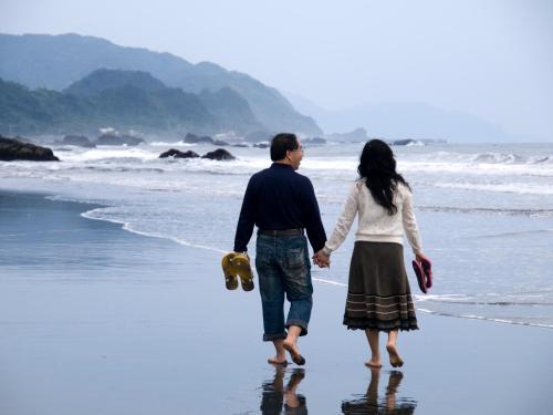 a man and a woman walking on the beach at 真情非凡行館 Sealuv Homestay in Toucheng