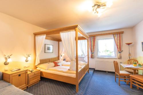 a bedroom with a canopy bed with a desk and a table at Hotel - Pension Scheiblechner in Göstling an der Ybbs