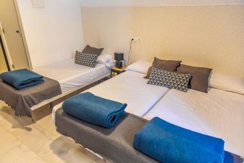 Dos camas en una habitación con almohadas azules. en Feel Hostels Soho Malaga, en Málaga